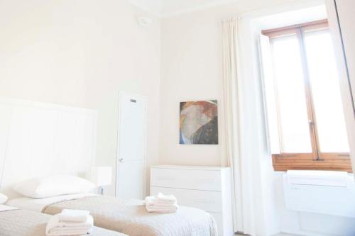 2 Betten in einem weißen Zimmer mit Fenster in der Unterkunft Tornabuoni Charming Apartment in Florenz