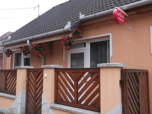 a house with a wooden fence with flowers on it at Apollo Vendégház in Edelény