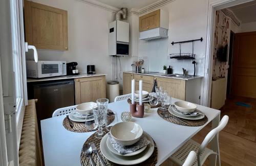 eine Küche mit einem weißen Tisch mit Tellern und Geschirr darauf in der Unterkunft L'éclat de Dieppe in Dieppe