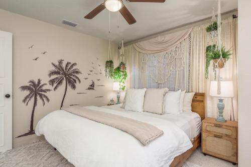 a bedroom with a white bed with palm trees on the wall at Luxury Home with Hot Tub & Outdoor Oasis blocks from the Beach in St Pete Beach