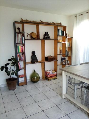 ein Wohnzimmer mit einem Tisch und Regalen mit Büchern in der Unterkunft Maison Gruissan Mateille in Gruissan