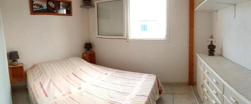 ein kleines Schlafzimmer mit einem Bett und einem Fenster in der Unterkunft Maison Gruissan Mateille in Gruissan