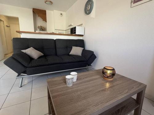 een woonkamer met een zwarte bank en een tafel bij Appartement T3 Duplex Saint Cast Le Guildo in LʼIsle-Saint-Cast