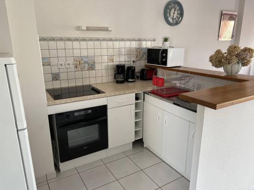 une cuisine avec des armoires blanches et un four à plaques de cuisson dans l'établissement Appartement T3 Duplex Saint Cast Le Guildo, à LʼIsle-Saint-Cast