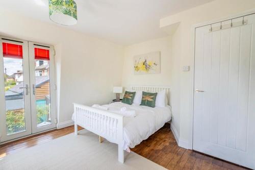 a white bedroom with a white bed and a window at Sea View Cottage Southwold in Southwold