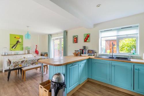 a kitchen with blue cabinets and a wooden counter top at Sea View Cottage Southwold in Southwold