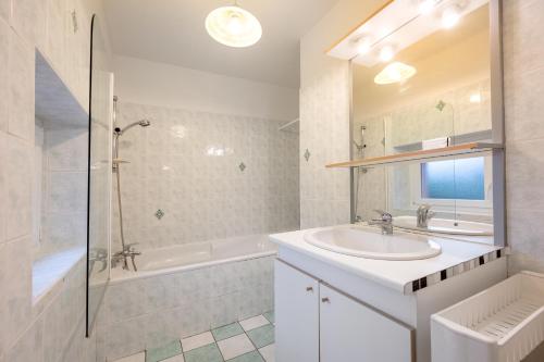 ein weißes Bad mit einem Waschbecken und einer Dusche in der Unterkunft Les Clématites in Hillion