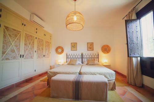 a bedroom with two beds and a large window at Hacienda El Rosalejo in Villamartín