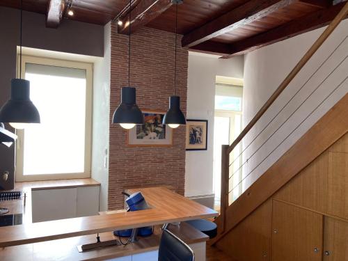 une salle à manger avec une table et un mur de briques dans l'établissement Duplex de la République, à Millau