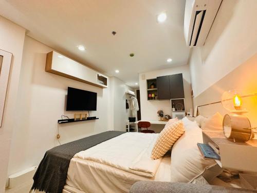 een slaapkamer met een bed, een bureau en een televisie bij Primo Condo Studio Type - One Pontefino Tower in Batangas City