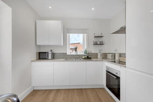 a white kitchen with white cabinets and a window at Bromstone House, Broadstairs in Broadstairs