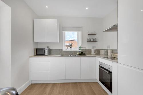 Una cocina blanca con gabinetes blancos y una ventana. en Bromstone House, Broadstairs, en Broadstairs
