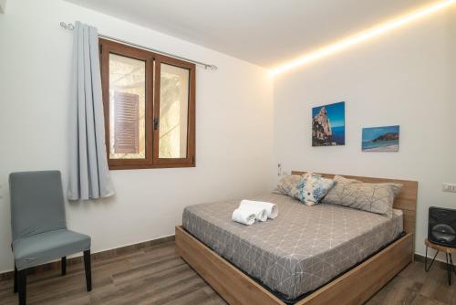 ein Schlafzimmer mit einem Bett, einem Stuhl und einem Fenster in der Unterkunft Mavi Piano Terra in Palau