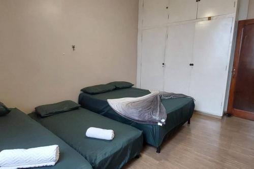 two green beds in a room with a closet at Conforto - Amplo 3 quartos no centro, perto de tudo, linda vista in Belo Horizonte