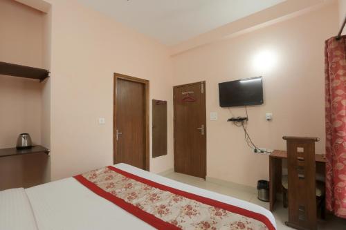 a bedroom with a bed and a flat screen tv at Hotel Ginger Palace By Aura in Noida