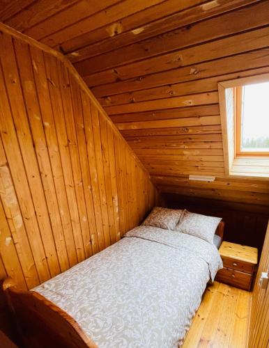 a bedroom with a bed in a wooden room at Viesu nams RŪĶĪŠI in Rugāji