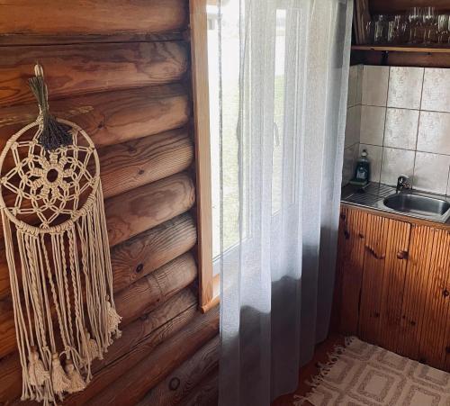 a kitchen with a wooden wall with a hanging basket at Viesu nams RŪĶĪŠI in Rugāji