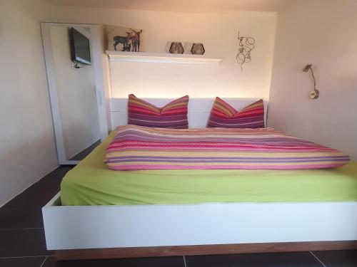 a bed with a green comforter and two pillows at Ferienhaus Schneekopf in Suhl