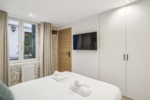 une chambre avec un lit blanc et une télévision dans l'établissement Cozy nest 2 steps from the Marais - 4 pers, à Paris