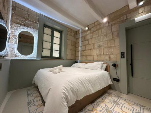 um quarto com uma cama grande e lençóis brancos em Lorenzo x Casa Norte em Birgu