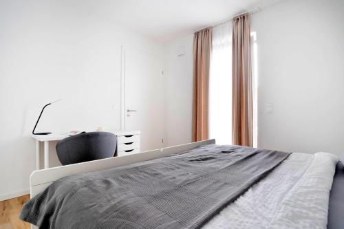a white bedroom with a bed and a desk at Moderne Apartments im Herzen von Osnabrück I private Tiefgarage I home2share in Osnabrück