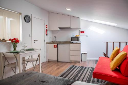 Una cocina y una sala de estar con un sofá rojo. en Praça Velha II - Estúdio no Centro de Braga, en Braga