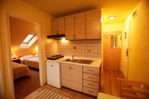 a kitchen with a sink and a room with a bed at Tribunia Beach Hotel in Tribunj