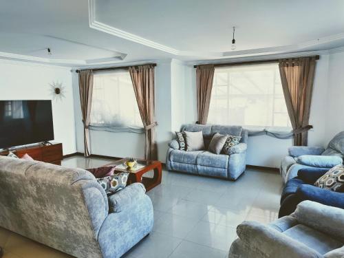 sala de estar con sofás azules y TV en Casa Quirola hermosa y muy grande en Cuenca