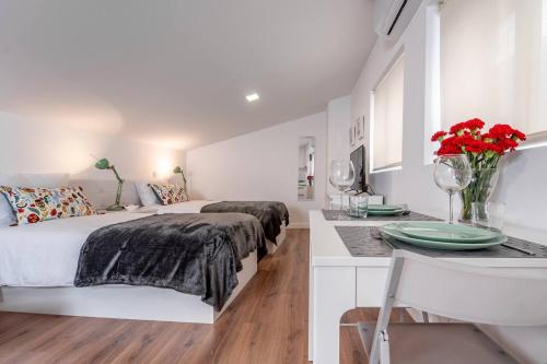 a white bedroom with a bed and a kitchen with a table at Praça Velha II - Estúdio no Centro de Braga in Braga