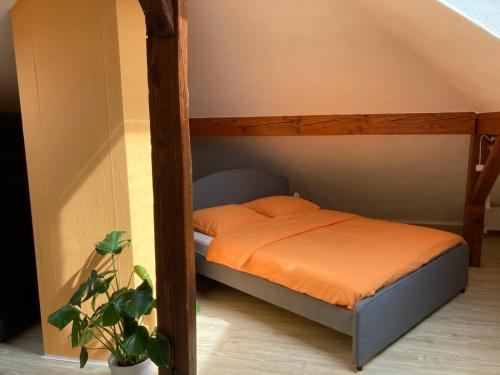 Bett mit orangefarbener Bettwäsche und Kissen in einem Zimmer in der Unterkunft NaturPur in Monschau