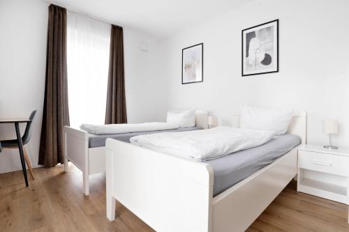 a white bedroom with two beds and a desk at Moderne Apartments im Herzen von Osnabrück I private Tiefgarage I home2share in Osnabrück