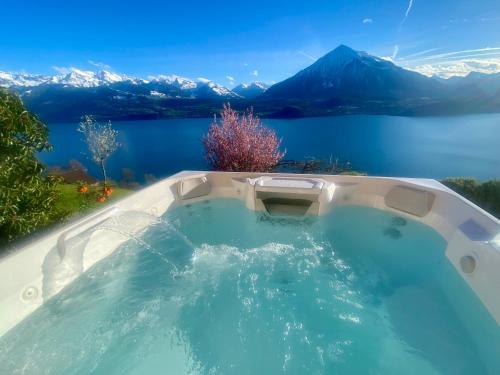 uma banheira de hidromassagem com vista para um lago e para as montanhas em CHALET EGGLEN "Typical Swiss House, Best Views, Private Jacuzzi" em Sigriswil