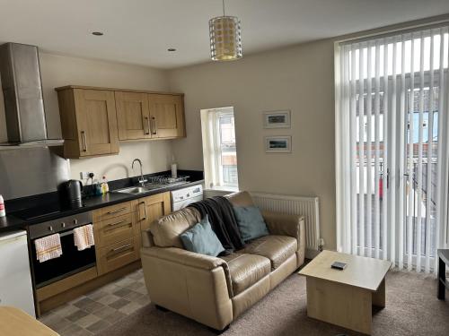 a living room with a couch and a kitchen at Norton Serviced Apartments in Stockton-on-Tees