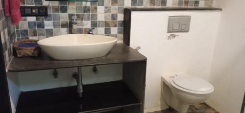 a bathroom with a sink and a toilet at Aranya Phansad Resort in Talekhār