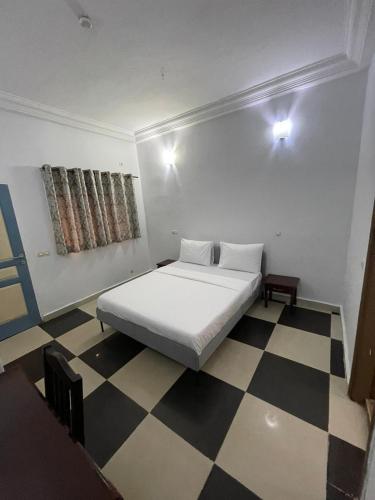 a bedroom with a white bed and a checkered floor at CHEZ SOPHIE in Conakry