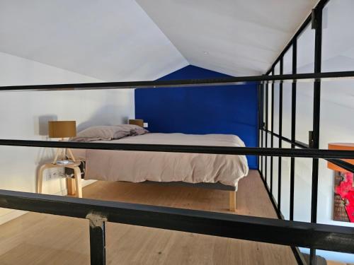 Ce lit superposé se trouve dans un dortoir doté d'un mur bleu. dans l'établissement Les Voyages du Loft, entre Eurexpo et St Exupéry, à Genas
