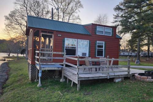a red tiny house with a porch and a bench at Wheeler Lake Riverbend Haven 2 in Stilwell