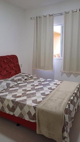 a bedroom with a large bed with a checkered blanket at LAZER EM GUARAJUBA in Guarajuba