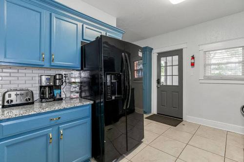 a kitchen with blue cabinets and a black refrigerator at Modern Comfort in Historic Charm: 4BR KC Retreat in Kansas City