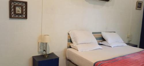 a bedroom with a bed with white sheets and pillows at Aranya Phansad Resort in Talekhār