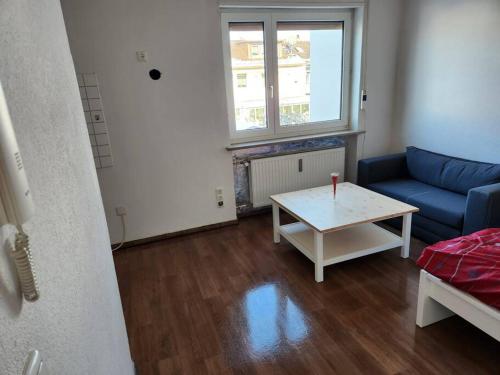 3: Einfache 1-Zimmer Wohnung in Bad Wörishofen في باد فوريسهوفن: غرفة معيشة مع أريكة زرقاء وطاولة