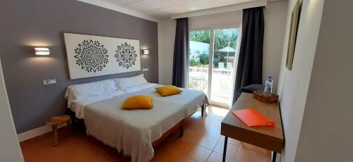 a bedroom with a bed with yellow pillows on it at Hostal Bahía Azul in Portocolom