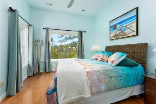 a bedroom with a bed with blue walls and a window at The TreeHouse by the Sea in Carolina Beach