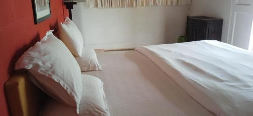 a bedroom with a bed with white sheets and pillows at Aranya Phansad Resort in Talekhār