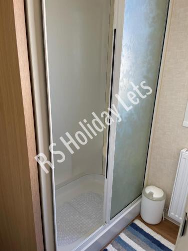 a glass shower door in a bathroom with a toilet at Starview 8 berth Caravan in Chapel Saint Leonards