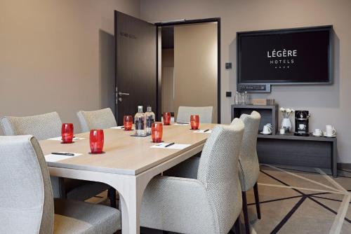 a conference room with a table with chairs and a television at LÉGÈRE HOTEL Bielefeld in Bielefeld