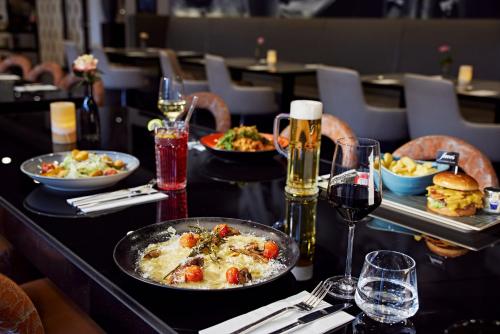 a table with plates of food and glasses of wine at LÉGÈRE HOTEL Bielefeld in Bielefeld