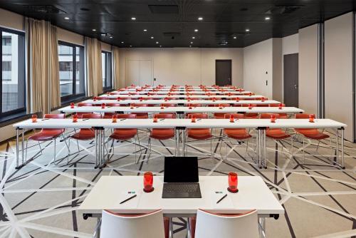a large room with tables and chairs and a laptop at LÉGÈRE HOTEL Bielefeld in Bielefeld