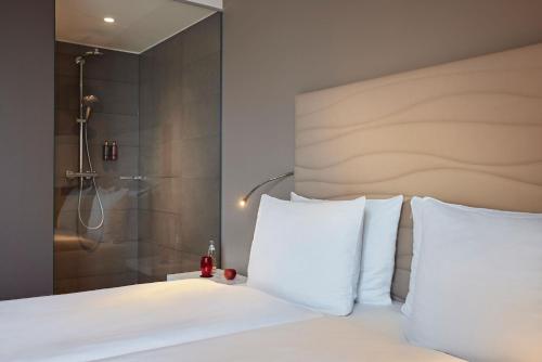 a bedroom with a white bed and a shower at LÉGÈRE HOTEL Bielefeld in Bielefeld