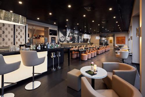 a restaurant with a bar with tables and chairs at LÉGÈRE HOTEL Bielefeld in Bielefeld